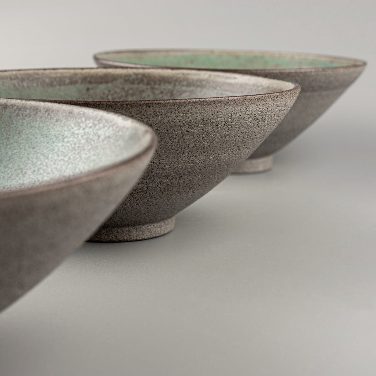 Detail of stacked ceramic bowls with interior glaze and exterior raw finish.