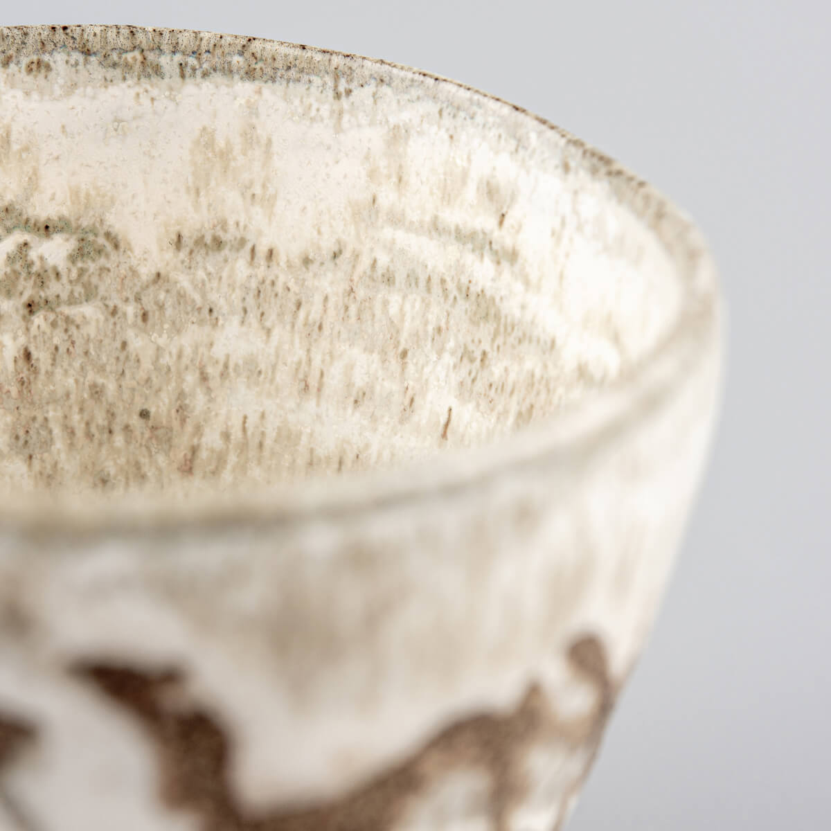 Handmade ceramic mug close-up with matte white glaze and carved stoneware details for fine dining presentation.