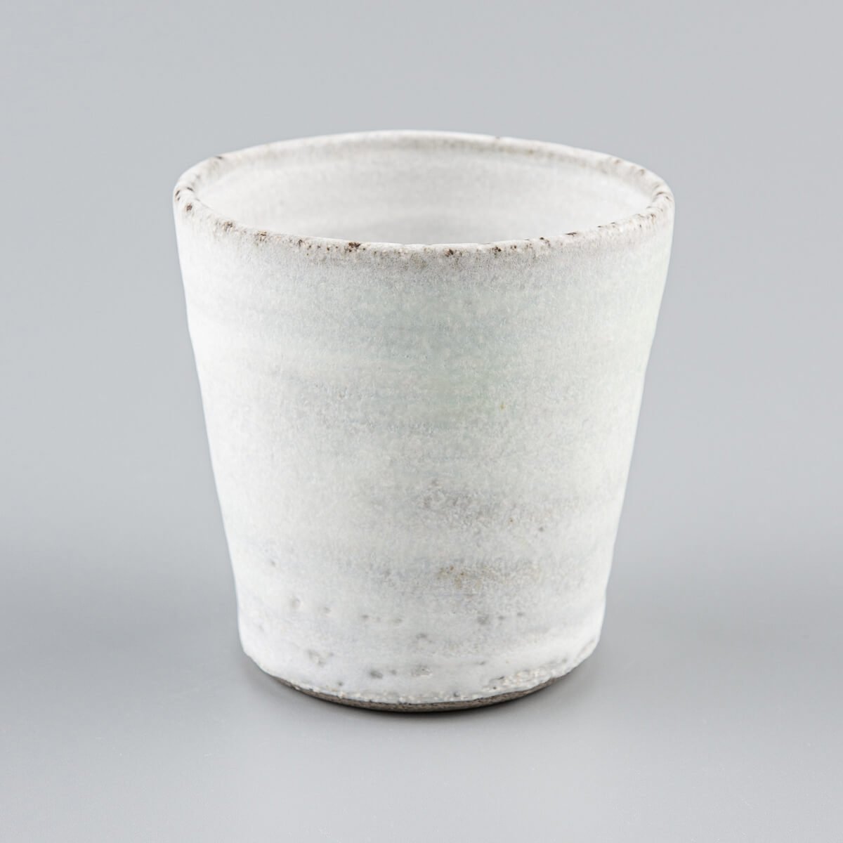 Elegant handmade ceramic mug with natural texture and beveled base for everyday kitchenware.