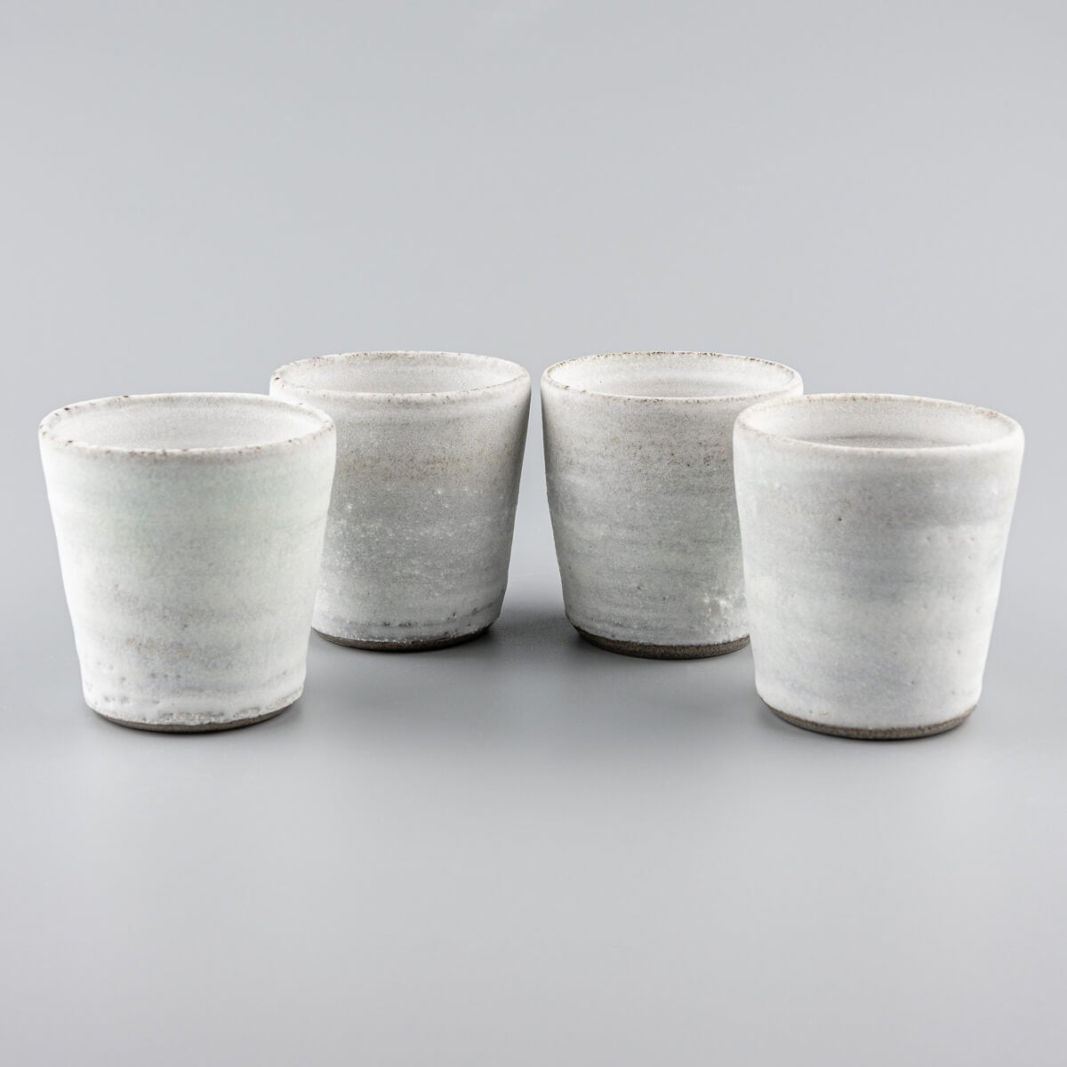 Set of artisanal stoneware mugs with minimalist white glaze, perfect for boutique hotels and fine dining.