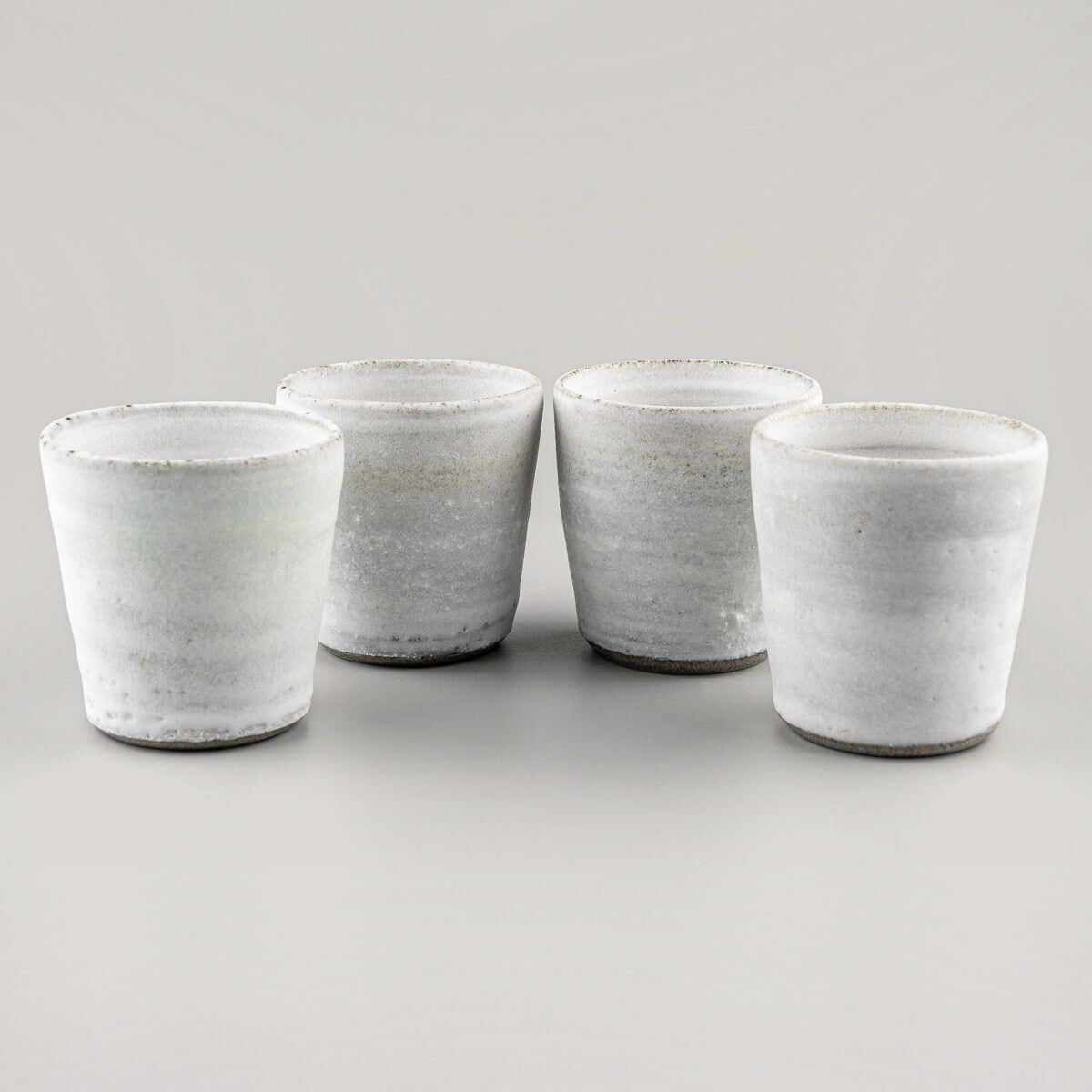 Set of artisanal stoneware mugs with minimalist white glaze, perfect for boutique hotels and fine dining.