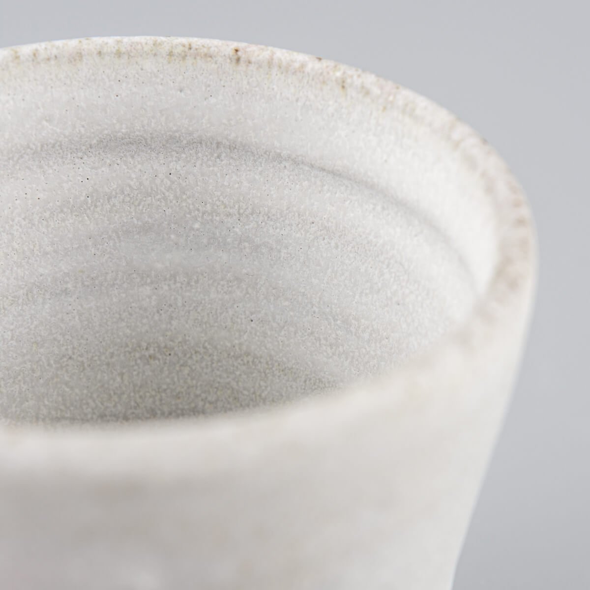 Close-up of handmade stoneware mug showing natural clay texture and minimalist glaze.