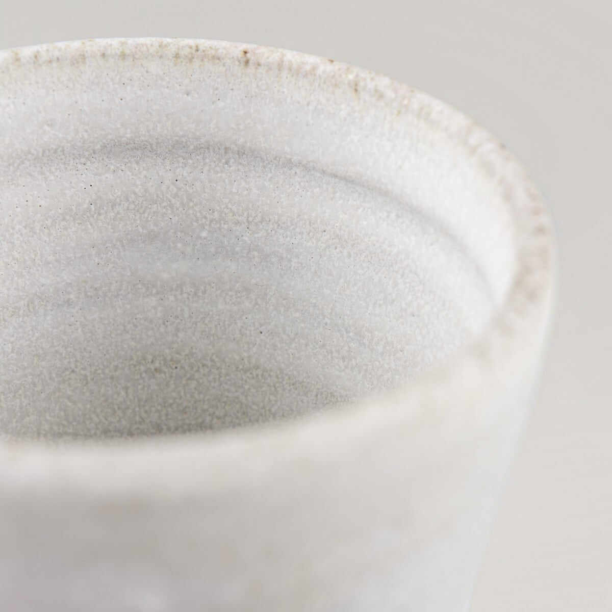 Close-up of handmade stoneware mug showing natural clay texture and minimalist glaze.