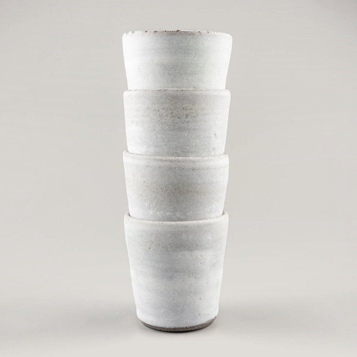 Vertical arrangement of handmade ceramic mugs with timeless design for tableware collections.