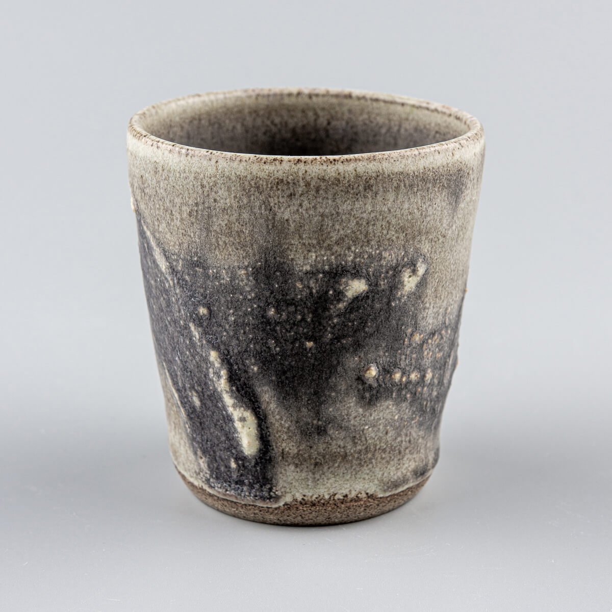 Artisanal stoneware pottery cup showing detailed texture and glaze, perfect for collectible pottery and home decor.