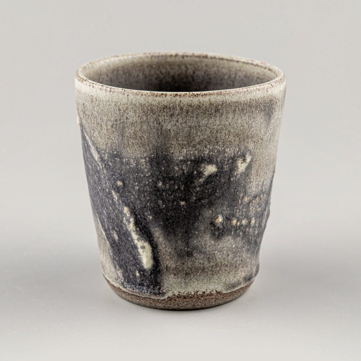 Artisanal stoneware pottery cup showing detailed texture and glaze, perfect for collectible pottery and home decor.