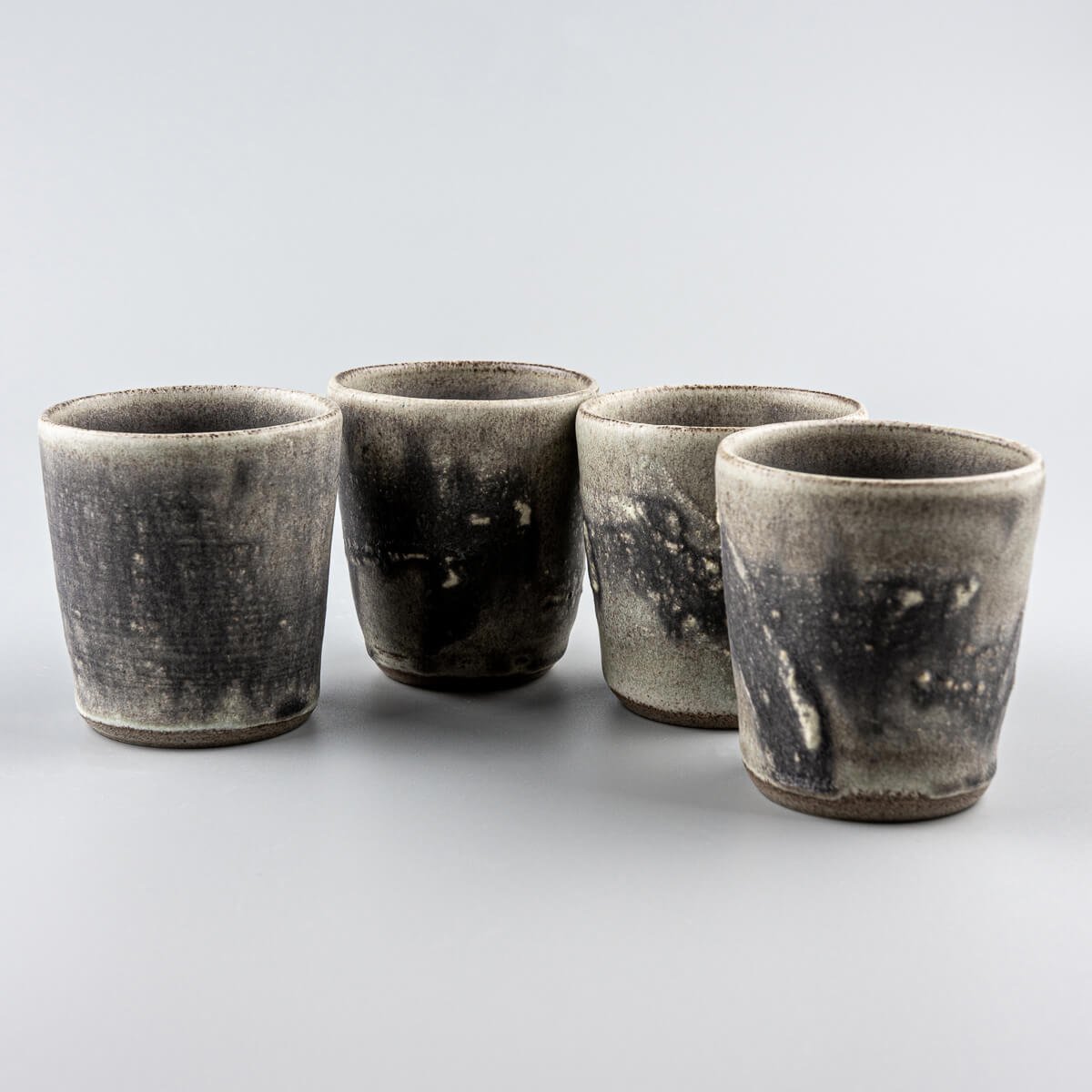 Handcrafted pottery cups set with olive-green glaze and textured hakeme surface, perfect for tea, coffee, and interior design.