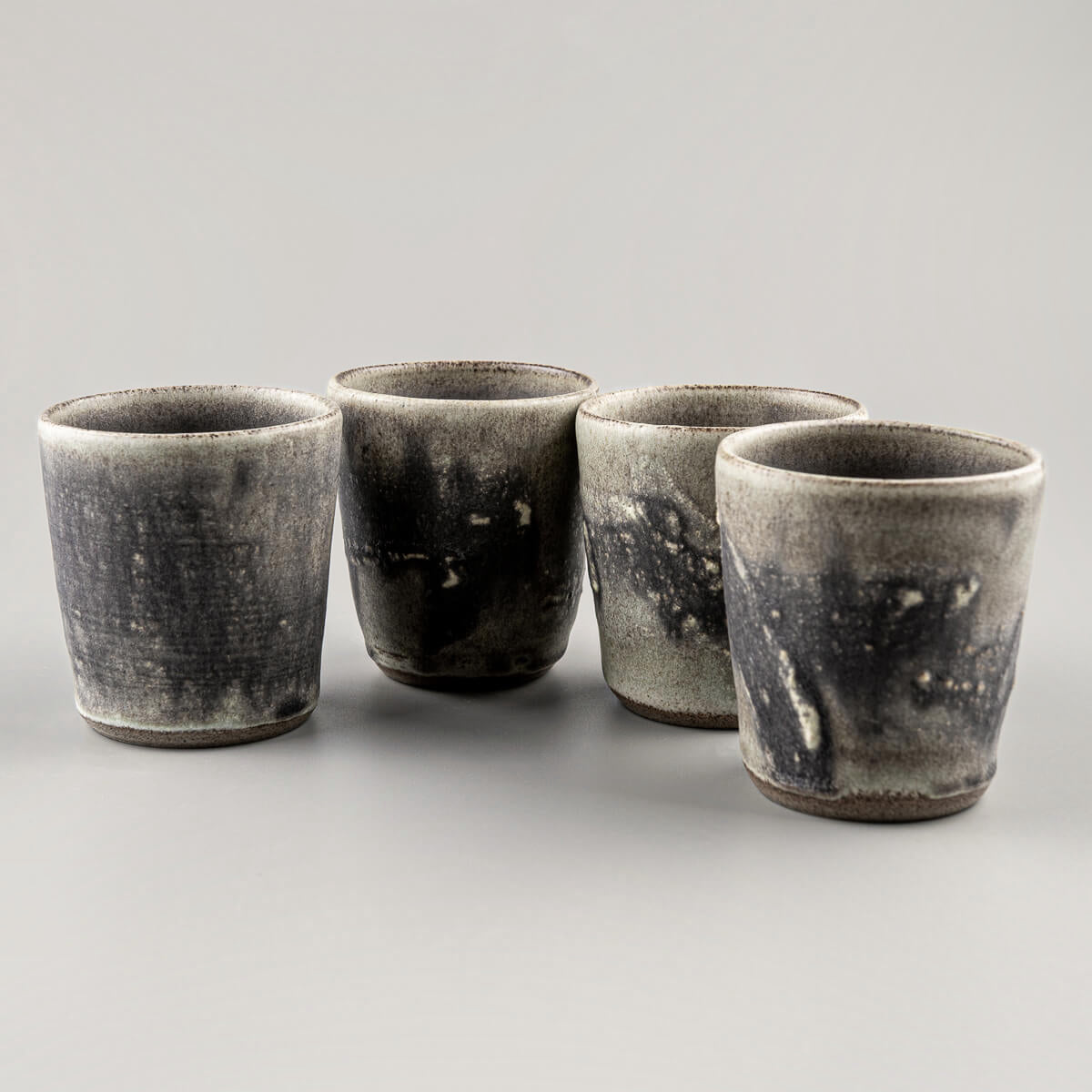 Handcrafted pottery cups set with olive-green glaze and textured hakeme surface, perfect for tea, coffee, and interior design.