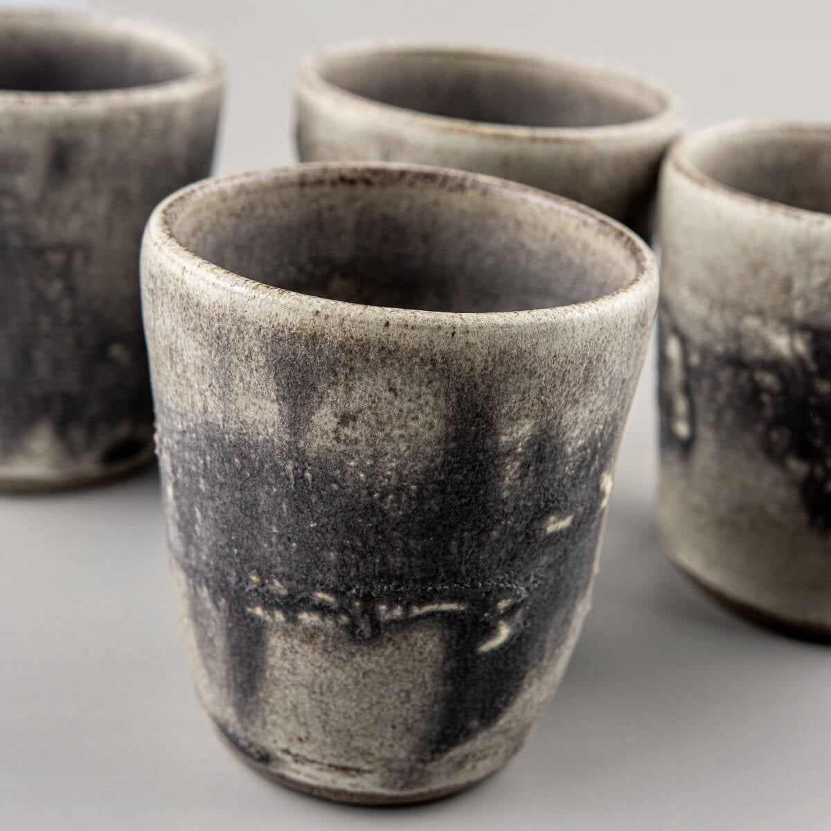Set of four pottery cups with rustic glaze and textured finish, designed for fine dining and boutique interiors.