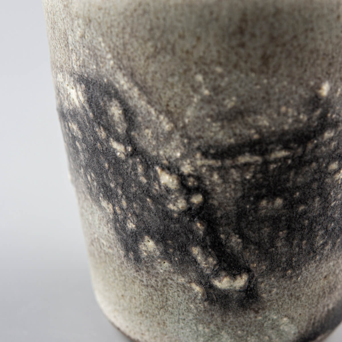 Close-up of textured ceramic glaze on pottery cup, highlighting artisanal detail and collectible pottery quality.