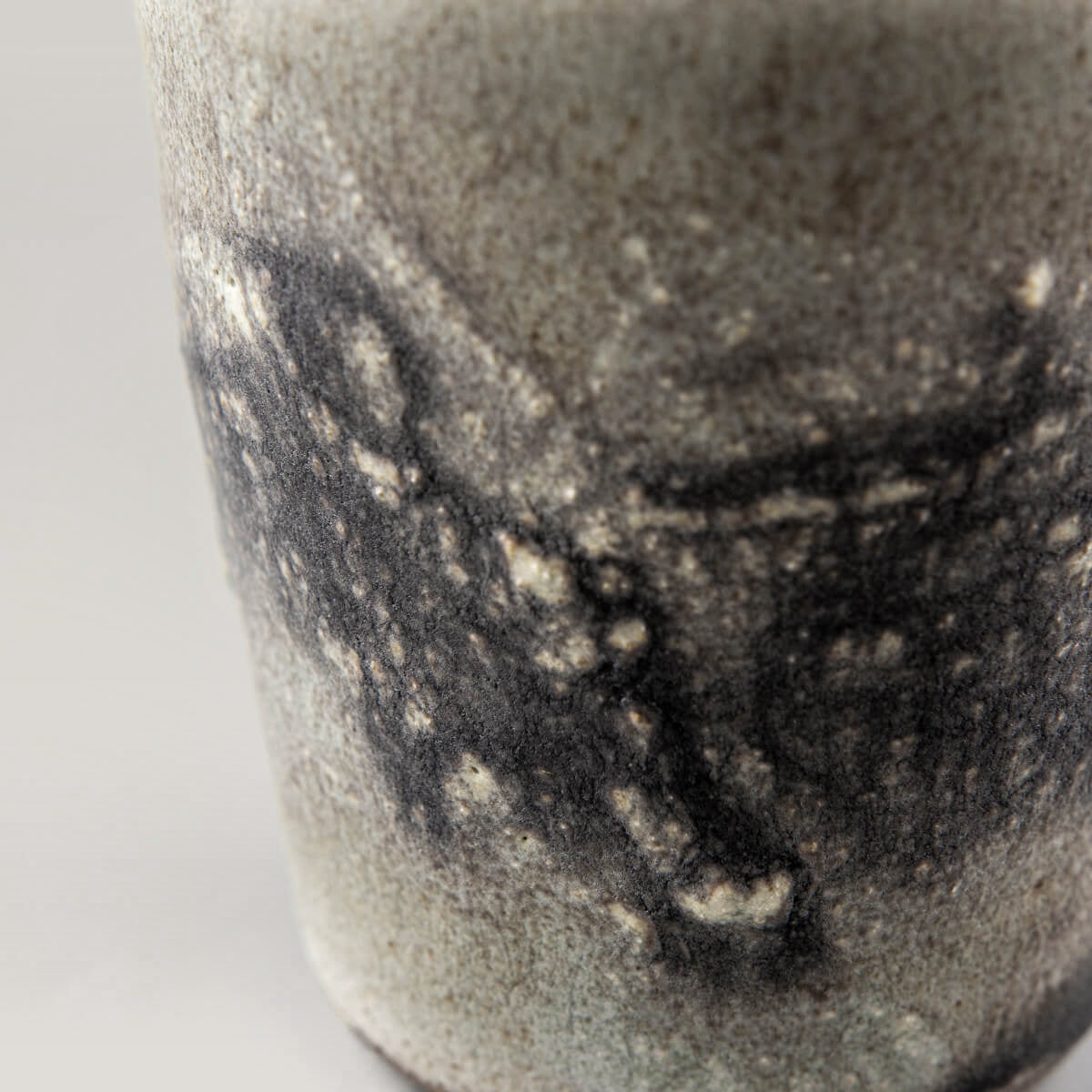 Close-up of textured ceramic glaze on pottery cup, highlighting artisanal detail and collectible pottery quality.