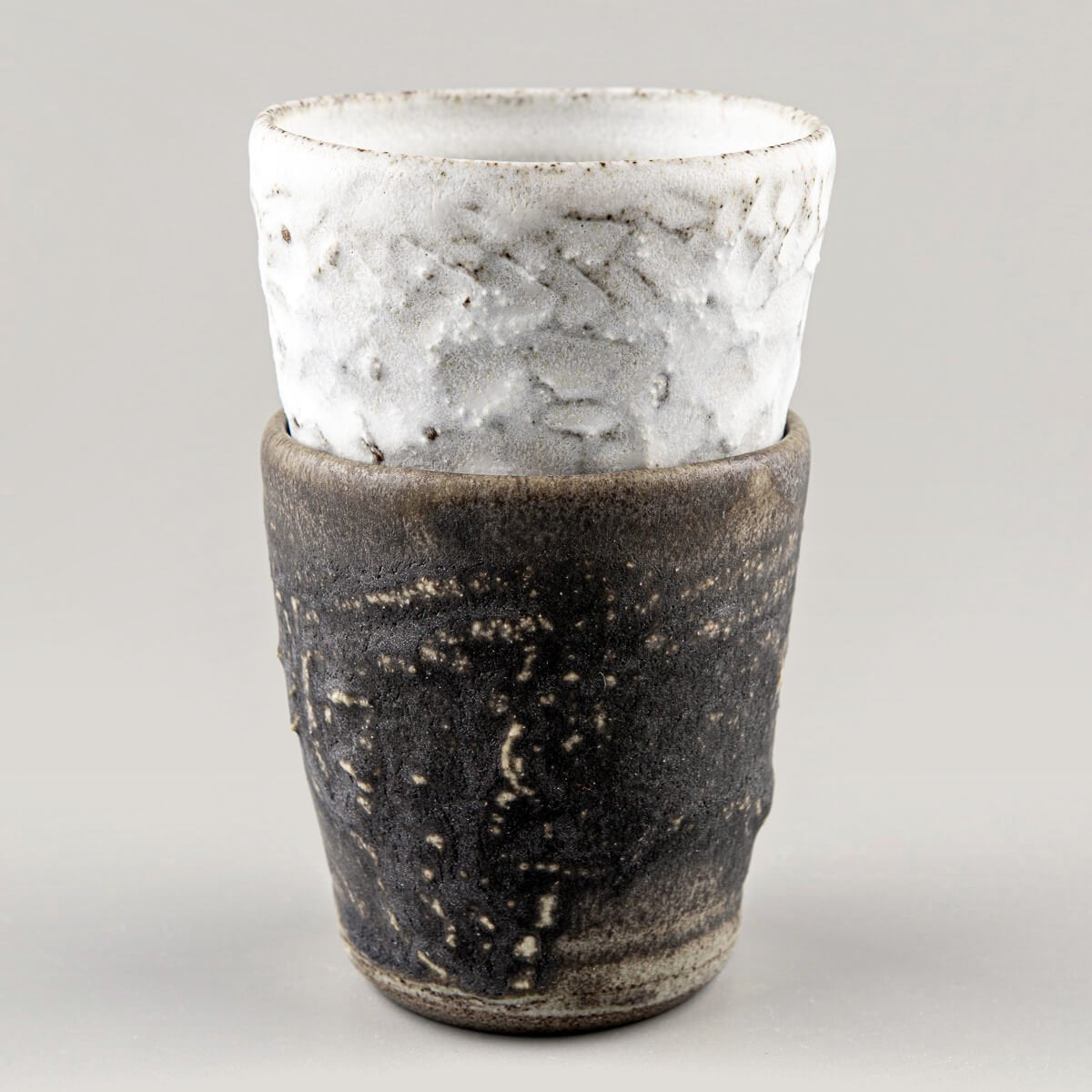 Paired stoneware mugs in contrasting dark and white glazes, crafted for home, restaurant, and luxury table settings.