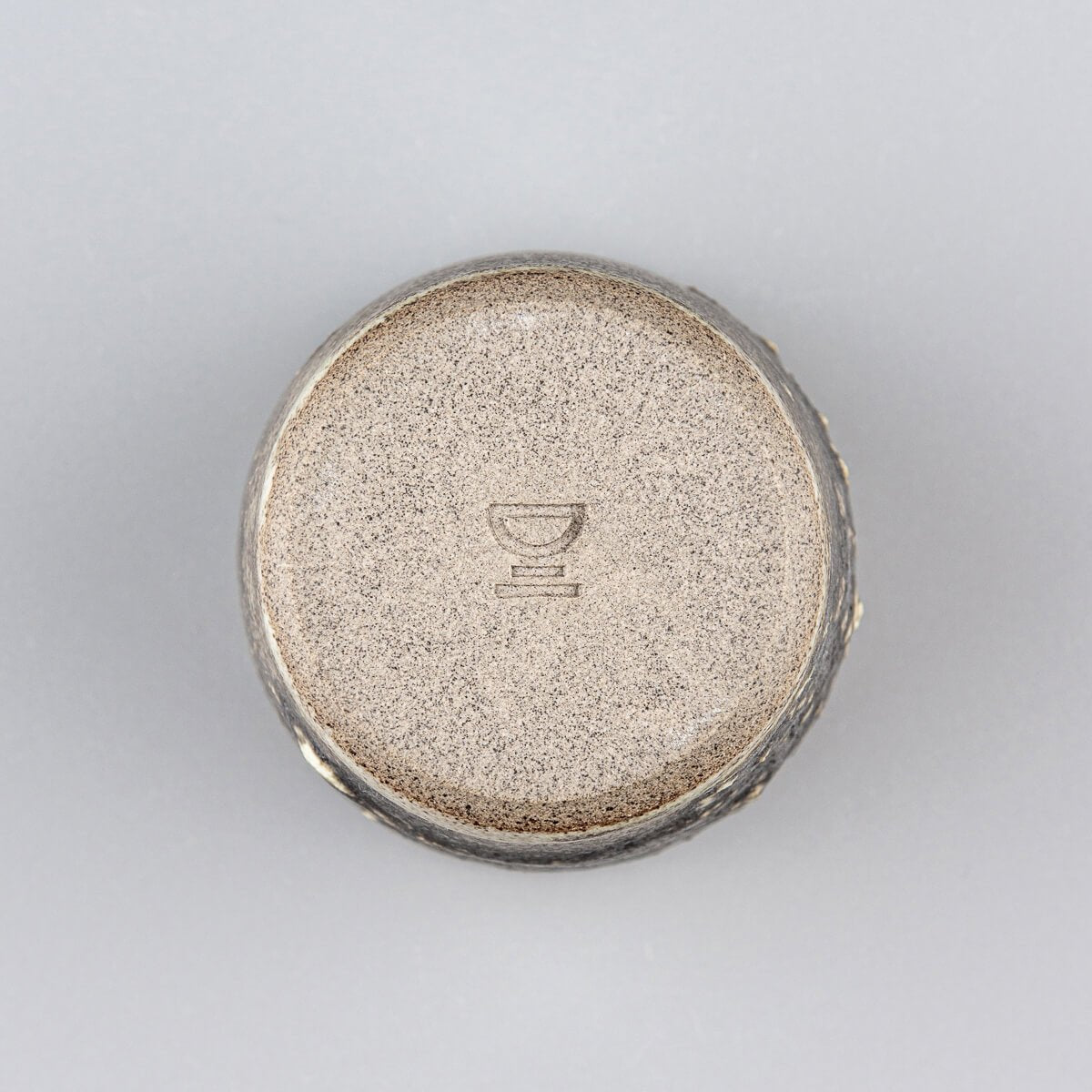 Bottom view of artisanal stoneware mug showing handmade details and natural clay finish for interior design collectors.