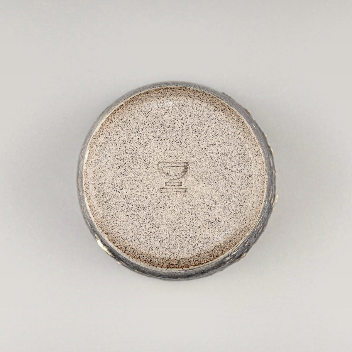 Bottom view of artisanal stoneware mug showing handmade details and natural clay finish for interior design collectors.