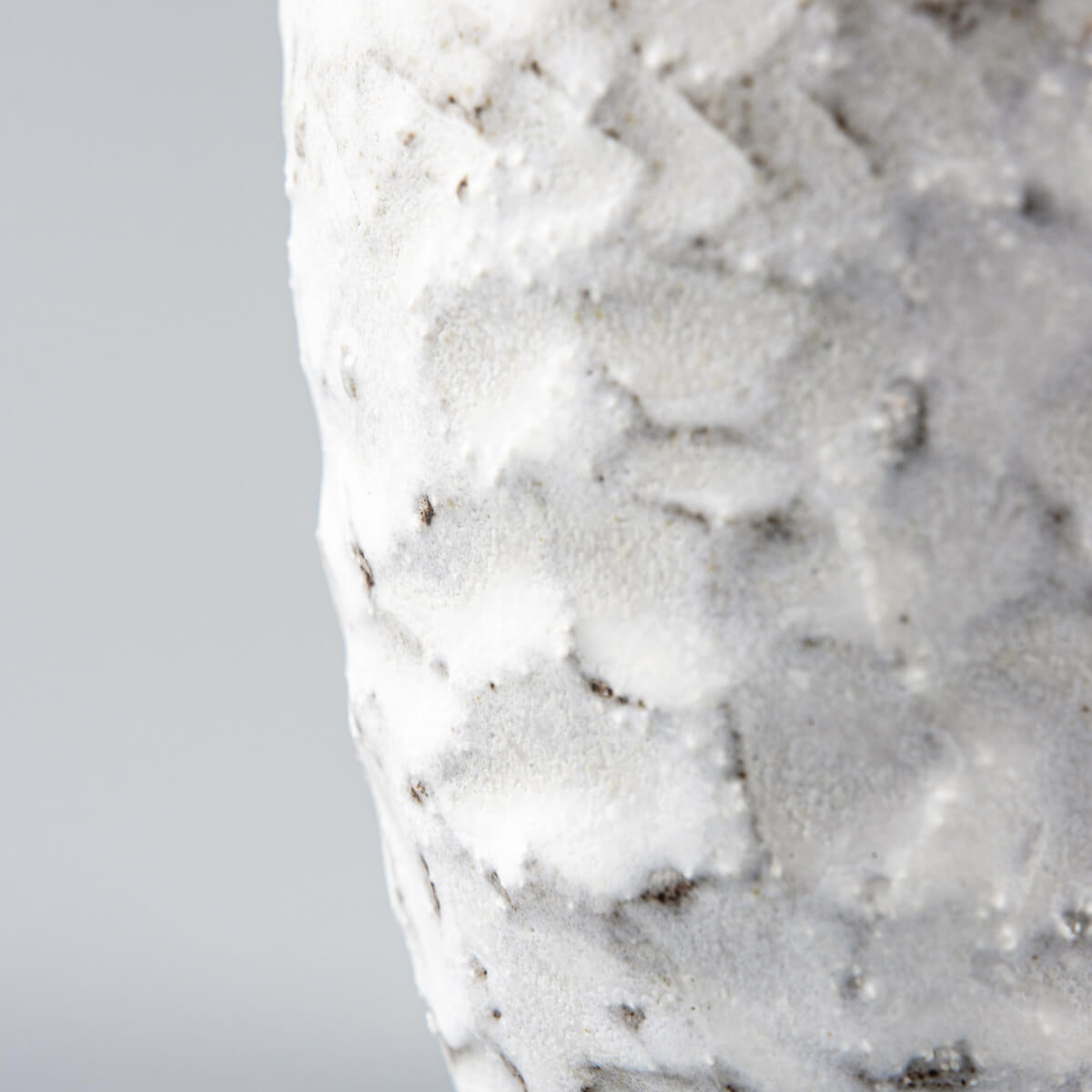 Close-up of a carved matte white ceramic mug with a textured surface for coffee, tea, and culinary presentation.