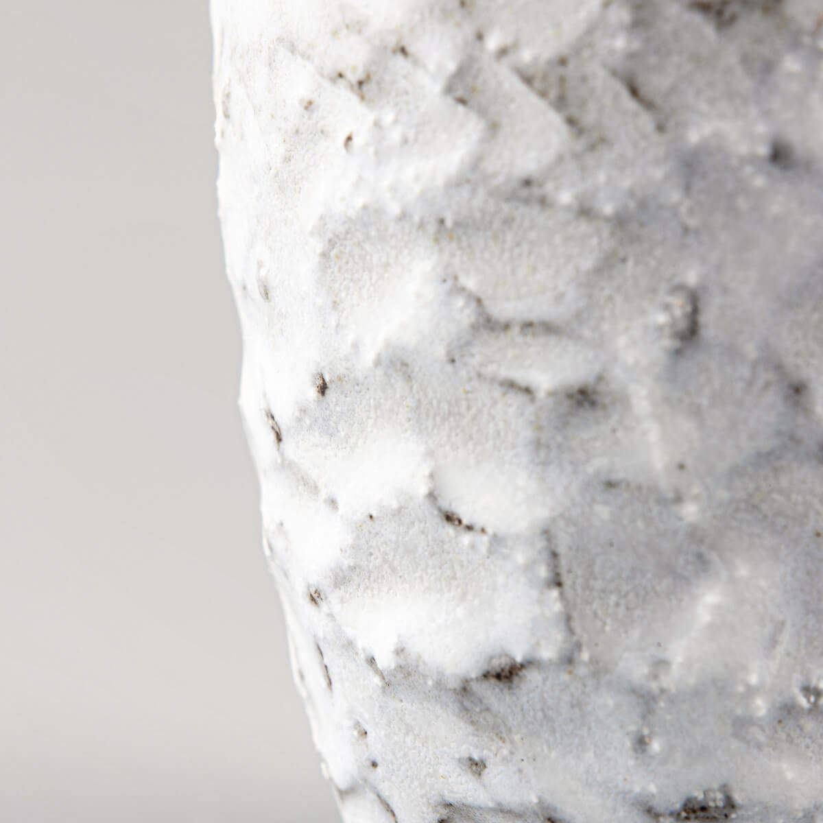 Close-up of a carved matte white ceramic mug with a textured surface for coffee, tea, and culinary presentation.