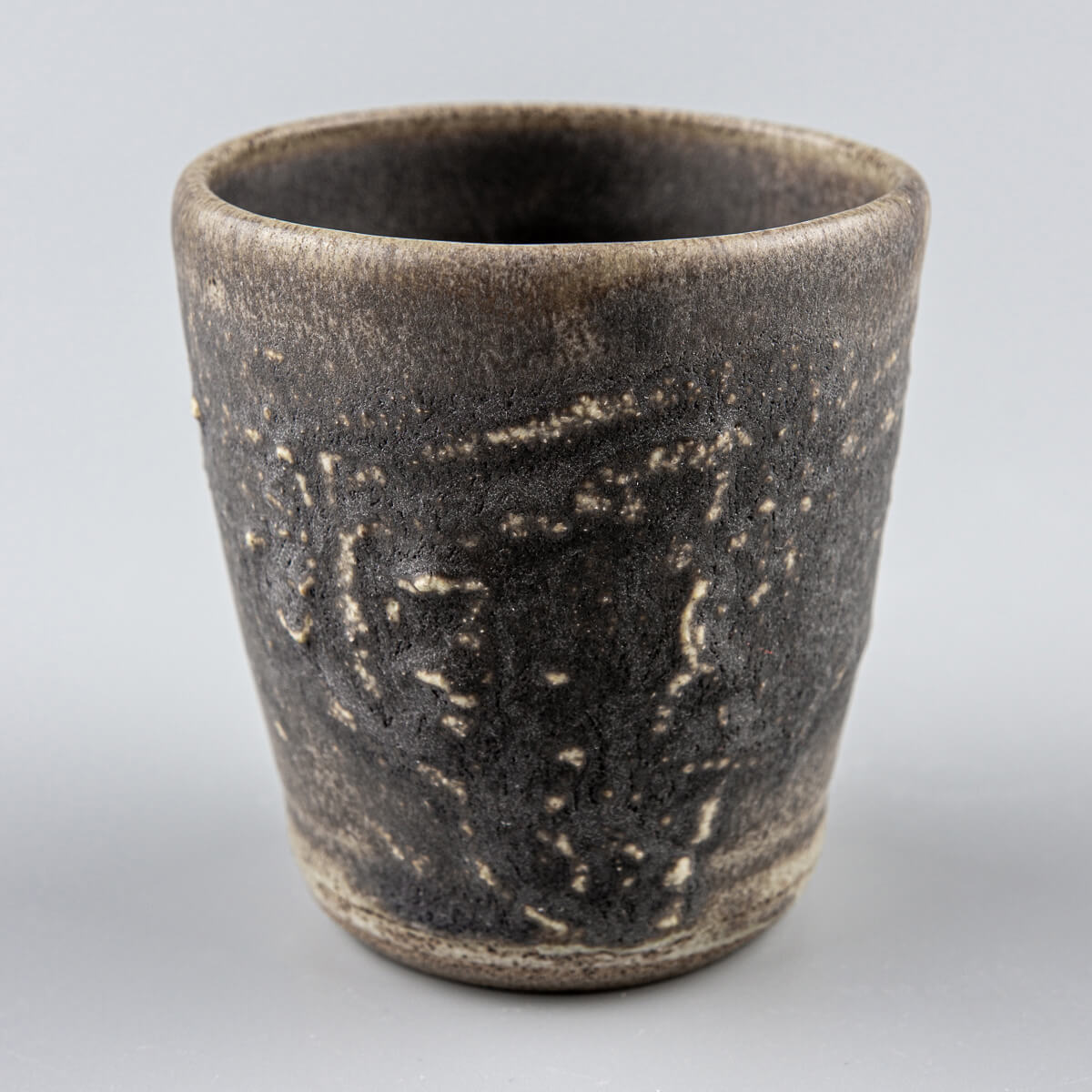 Dark stoneware mug with textured hakeme surface, perfect for coffee, tea, fine dining, and handmade decor.