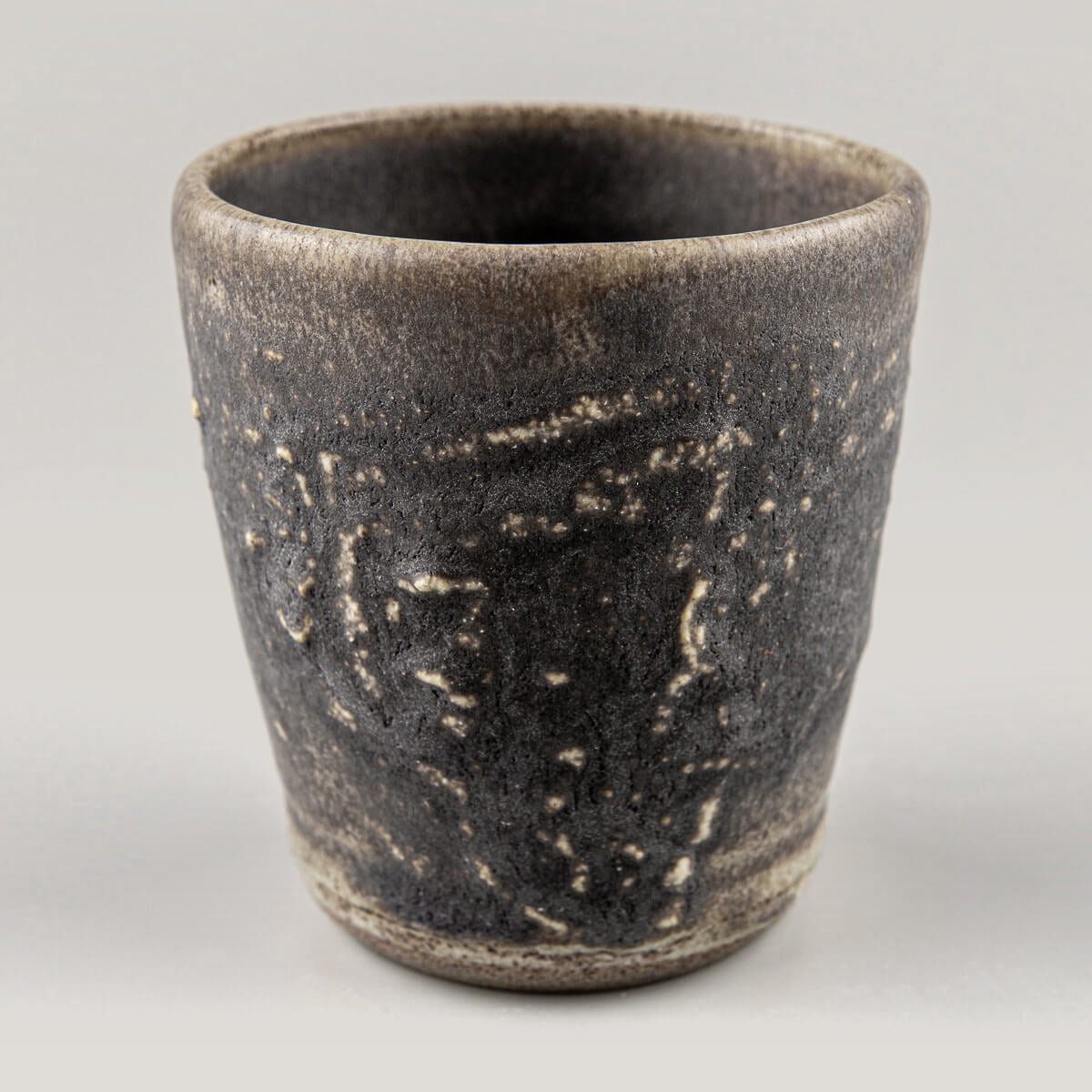 Dark stoneware mug with textured hakeme surface, perfect for coffee, tea, fine dining, and handmade decor.