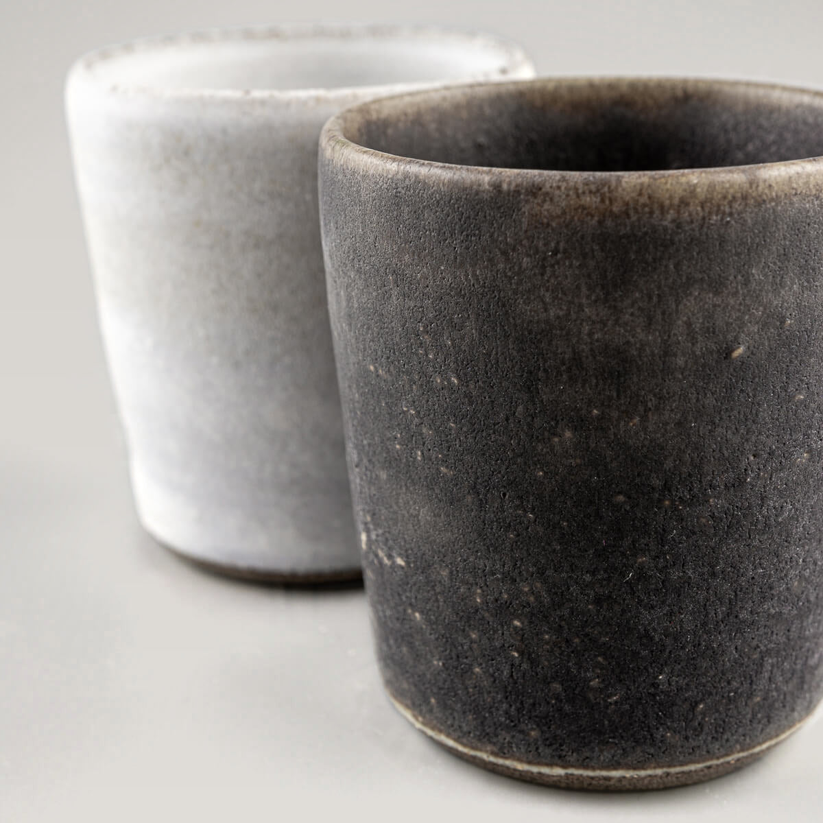 Two handcrafted ceramic cups showcasing the hakeme technique, designed for culinary presentation.