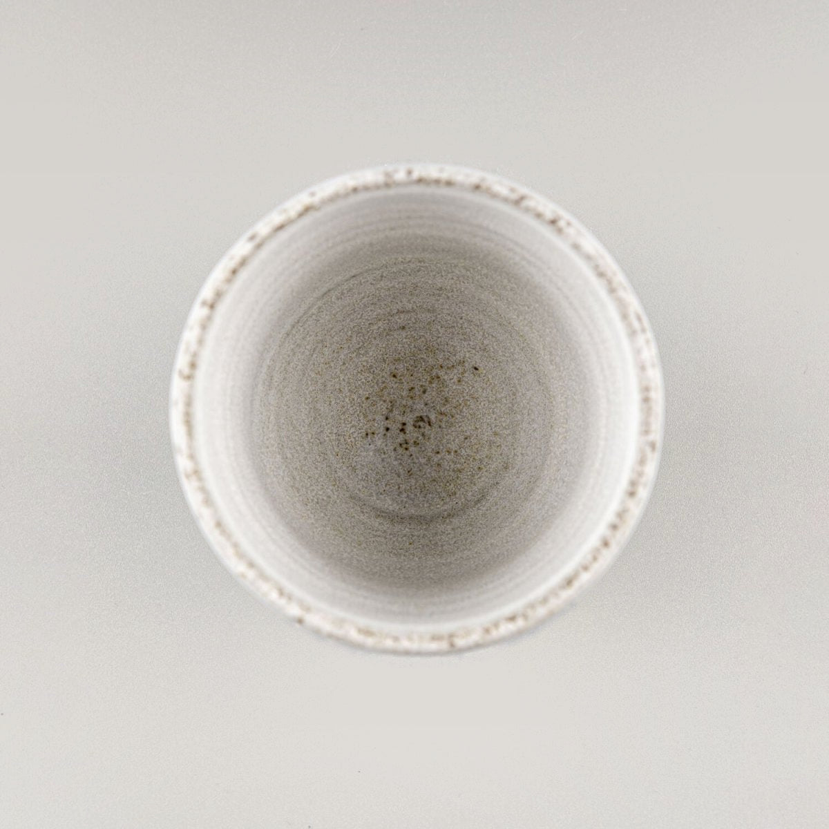 Artisanal pottery cup set combining rustic dark glaze and refined white finish for boutique hotels.