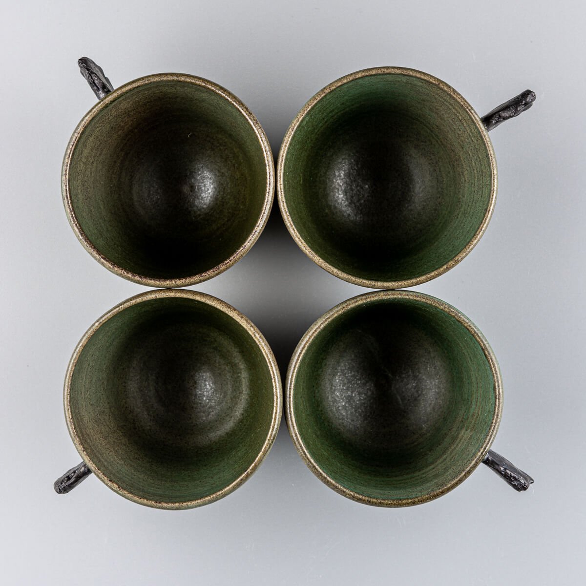 Top view of four handmade pottery mugs with green matte glaze, ideal for coffee, tea, or matcha rituals.