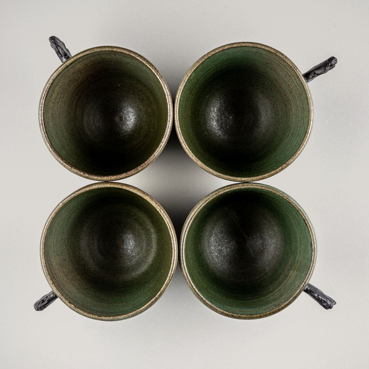 Top view of four handmade pottery mugs with green matte glaze, ideal for coffee, tea, or matcha rituals.