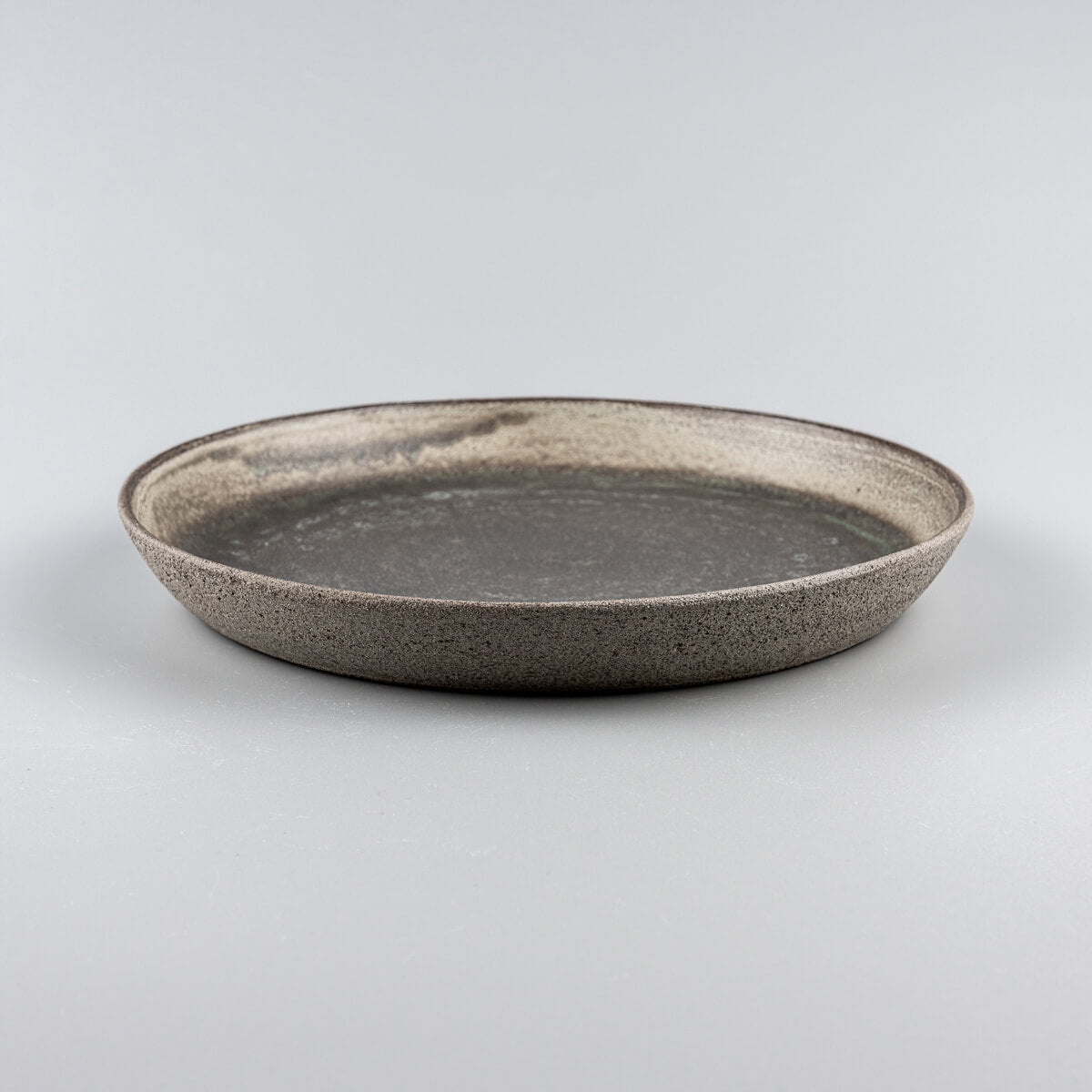 Close-up of textured dark stoneware plate with elegant matte glaze finish.