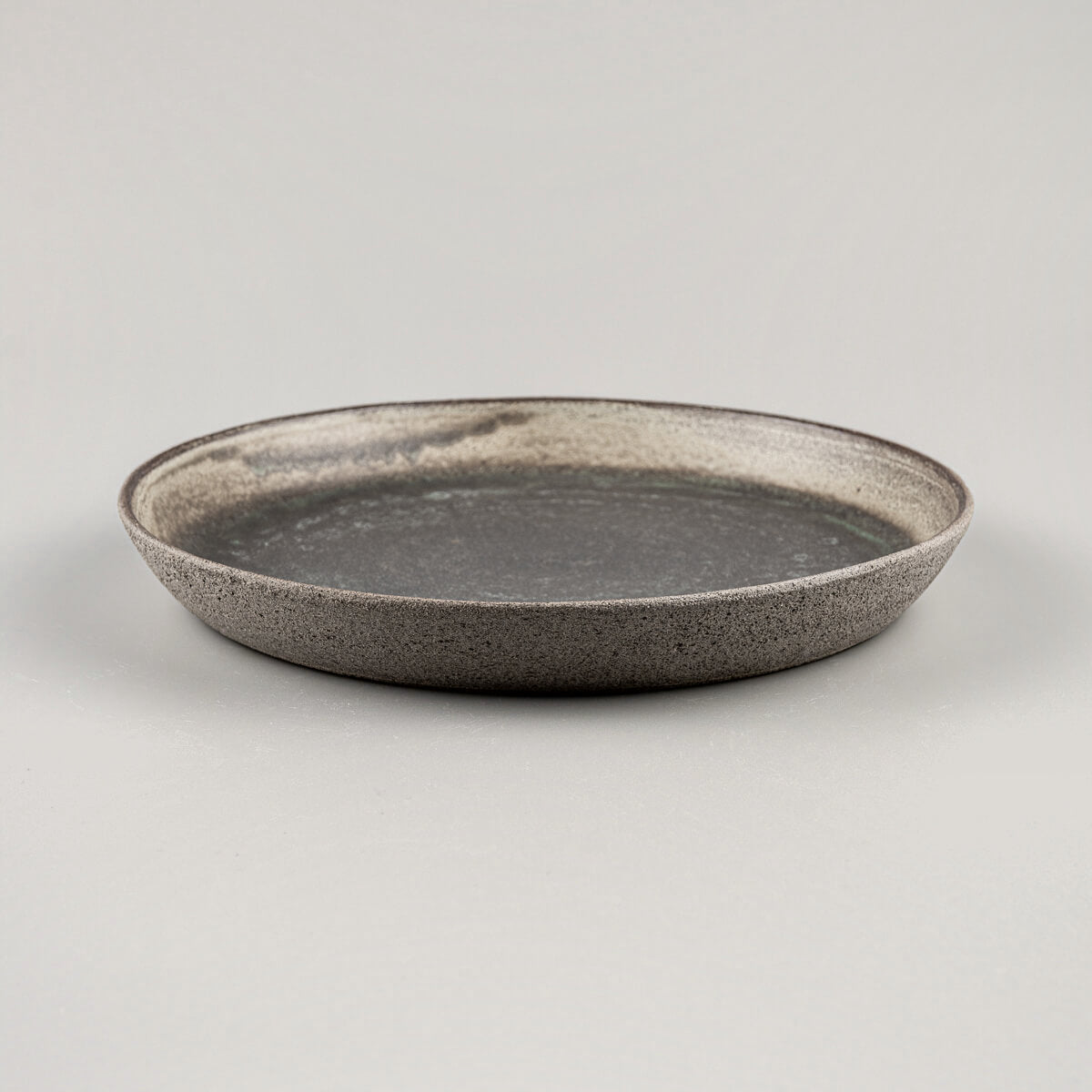 Close-up of textured dark stoneware plate with elegant matte glaze finish.
