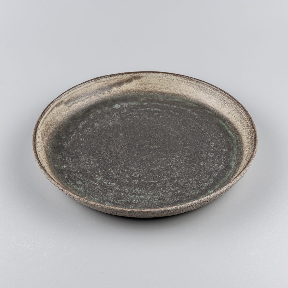 Side view of artisanal plate showcasing raised flat edges and smooth center.