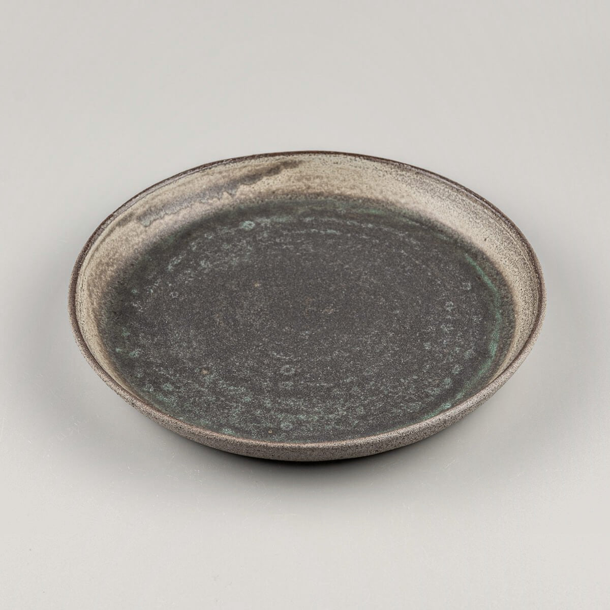 Side view of artisanal plate showcasing raised flat edges and smooth center.