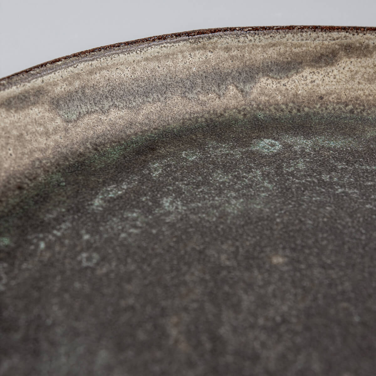 Detail of matte olive-green glaze on handcrafted stoneware plate.