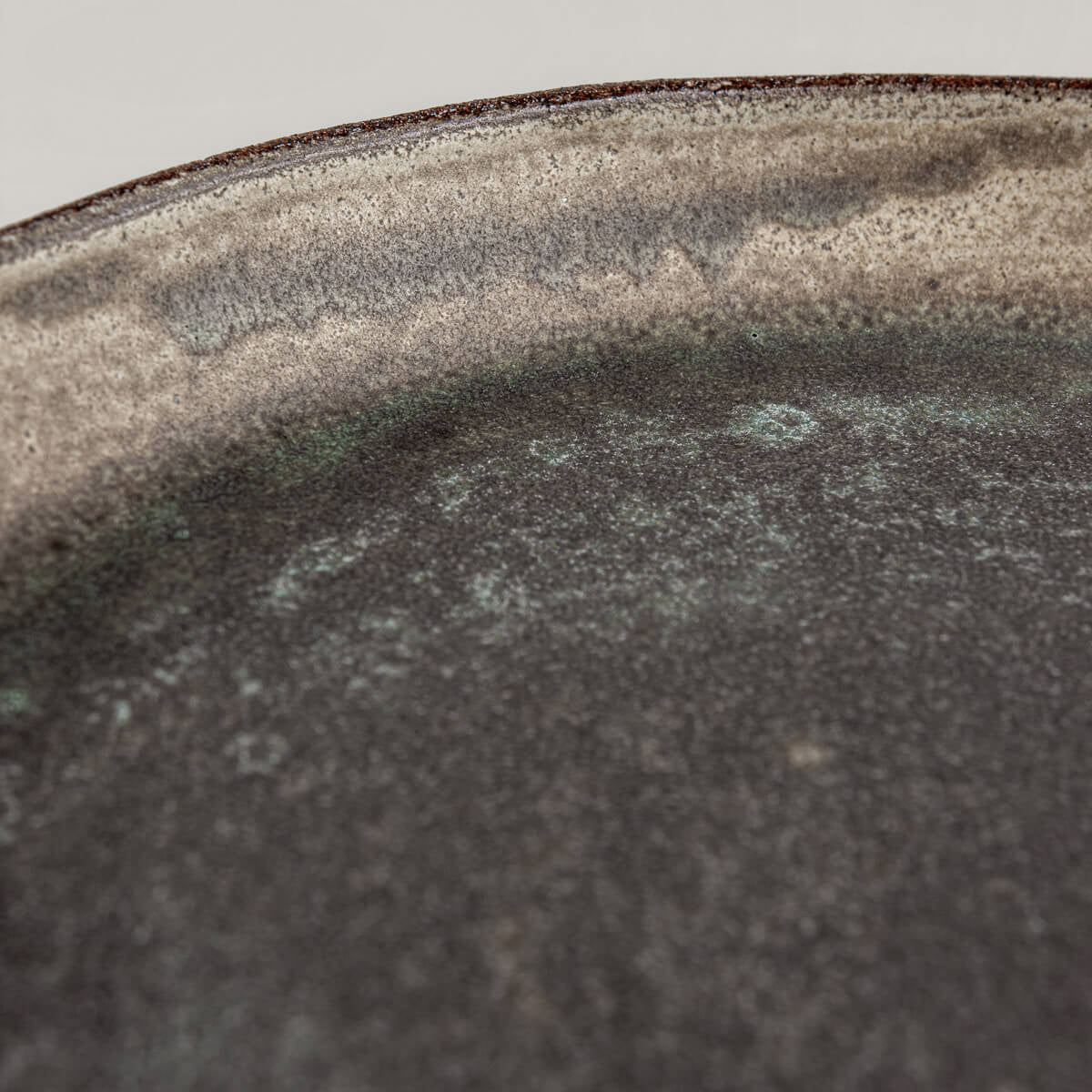 Detail of matte olive-green glaze on handcrafted stoneware plate.