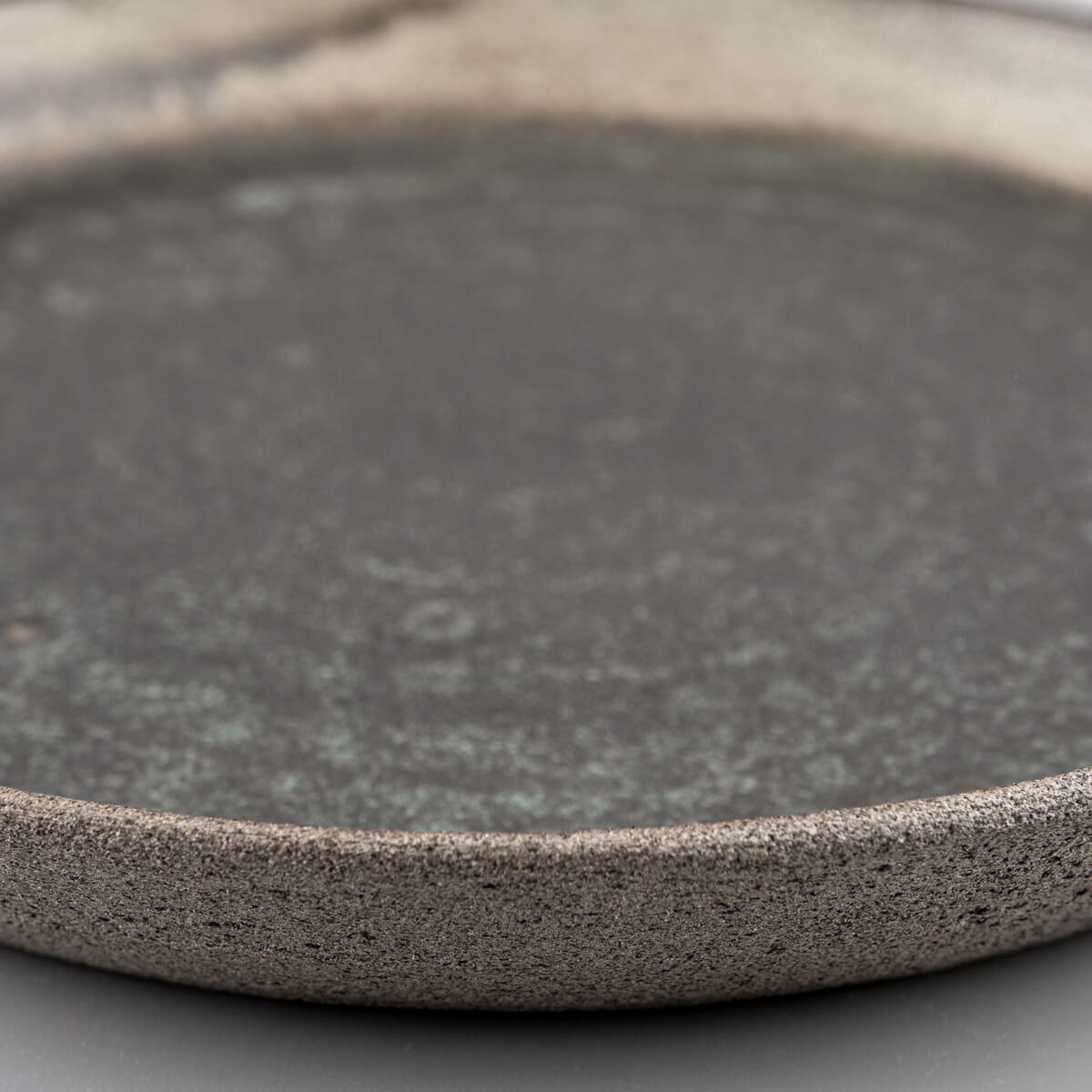 Artisan ceramic plate with unglazed exterior for natural stoneware texture.