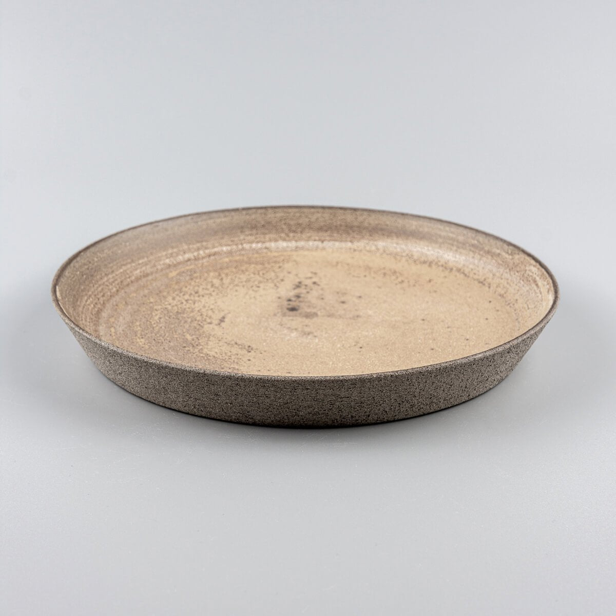 Handcrafted stoneware plate in warm ocher tones, perfect for gourmet restaurants.