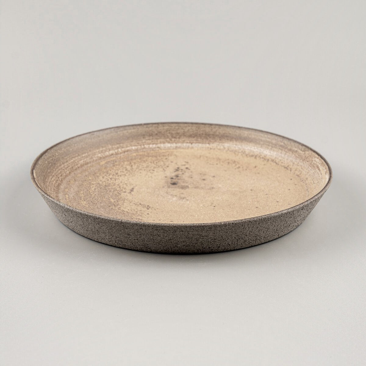 Handcrafted stoneware plate in warm ocher tones, perfect for gourmet restaurants.