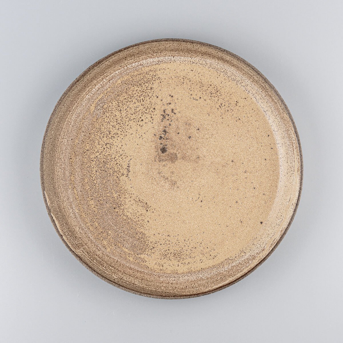 Stoneware dinner plate with matte ocher glaze and unglazed exterior for fine dining presentation.