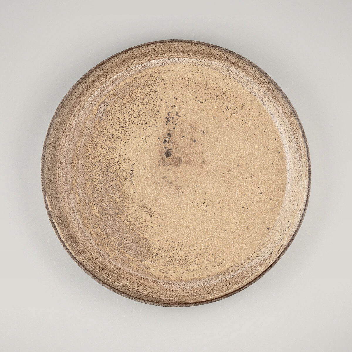 Stoneware dinner plate with matte ocher glaze and unglazed exterior for fine dining presentation.