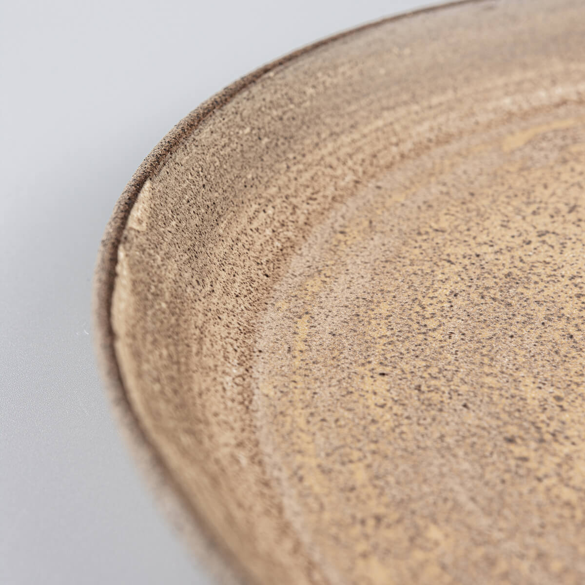 Coupe-style stoneware plate with textured unglazed exterior for luxury dining.