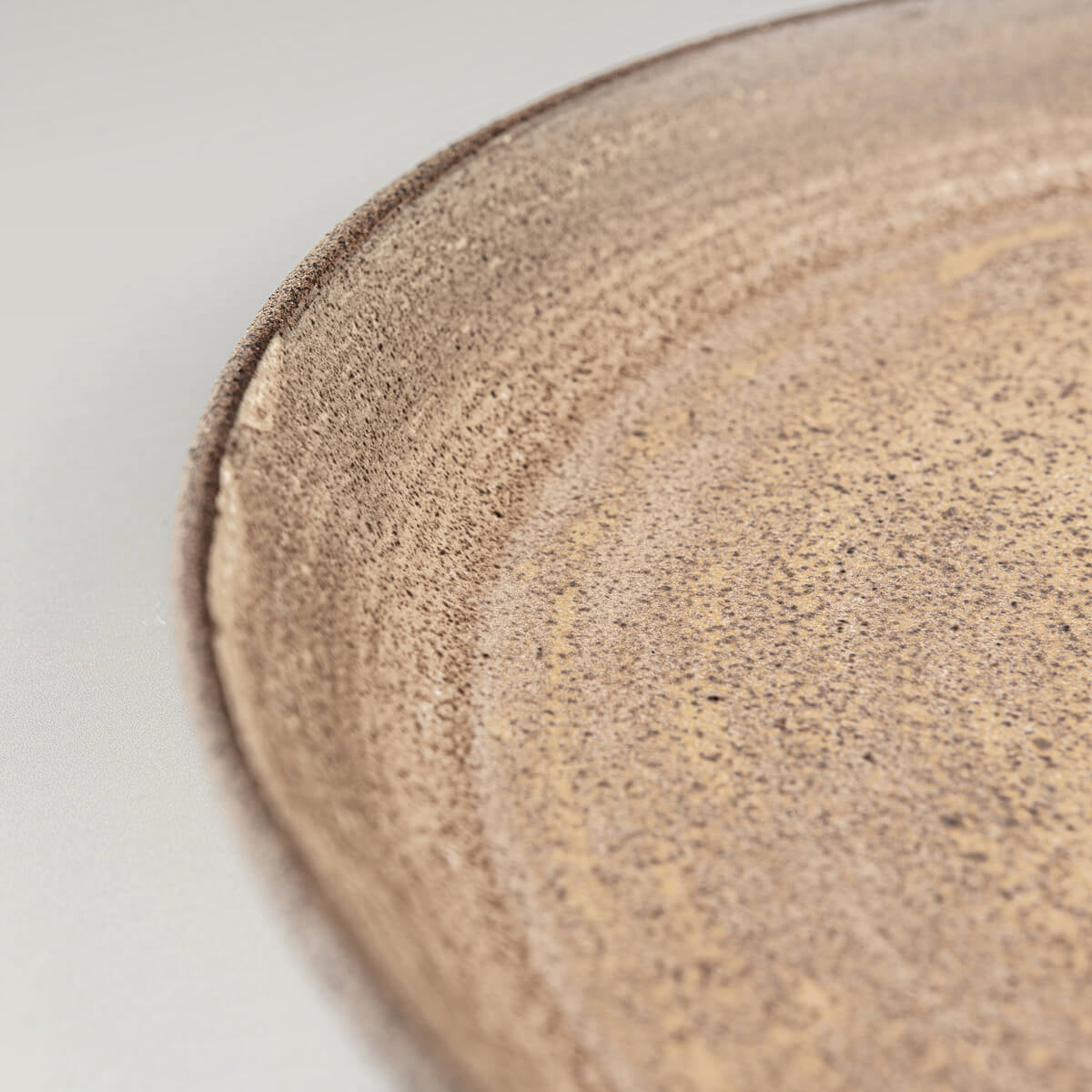 Coupe-style stoneware plate with textured unglazed exterior for luxury dining.