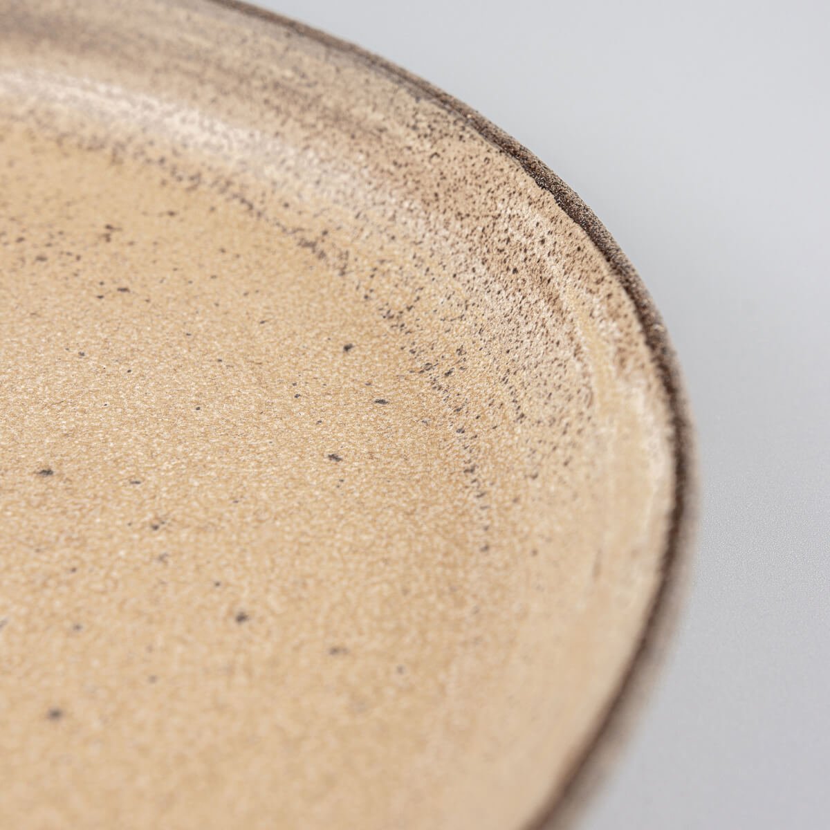 Elegant stoneware dinner plate with raised edges for refined culinary plating.