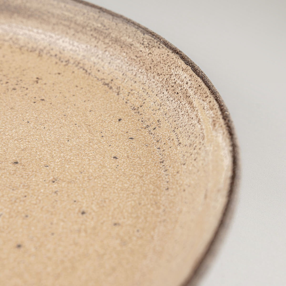 Elegant stoneware dinner plate with raised edges for refined culinary plating.