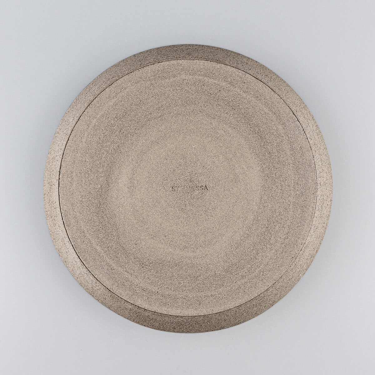 Underside view of stoneware dinner plate showcasing unglazed natural clay base.