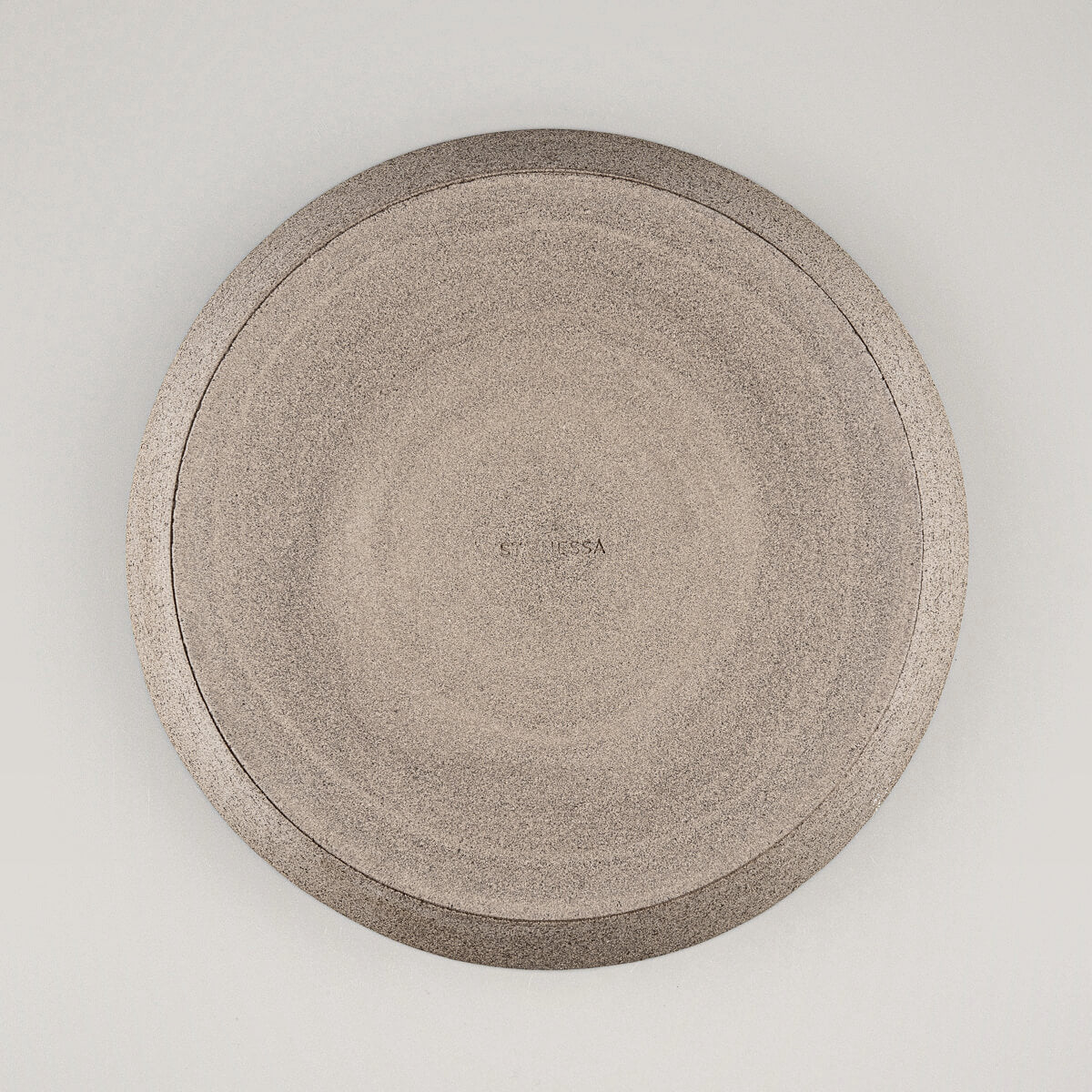 Underside view of stoneware dinner plate showcasing unglazed natural clay base.
