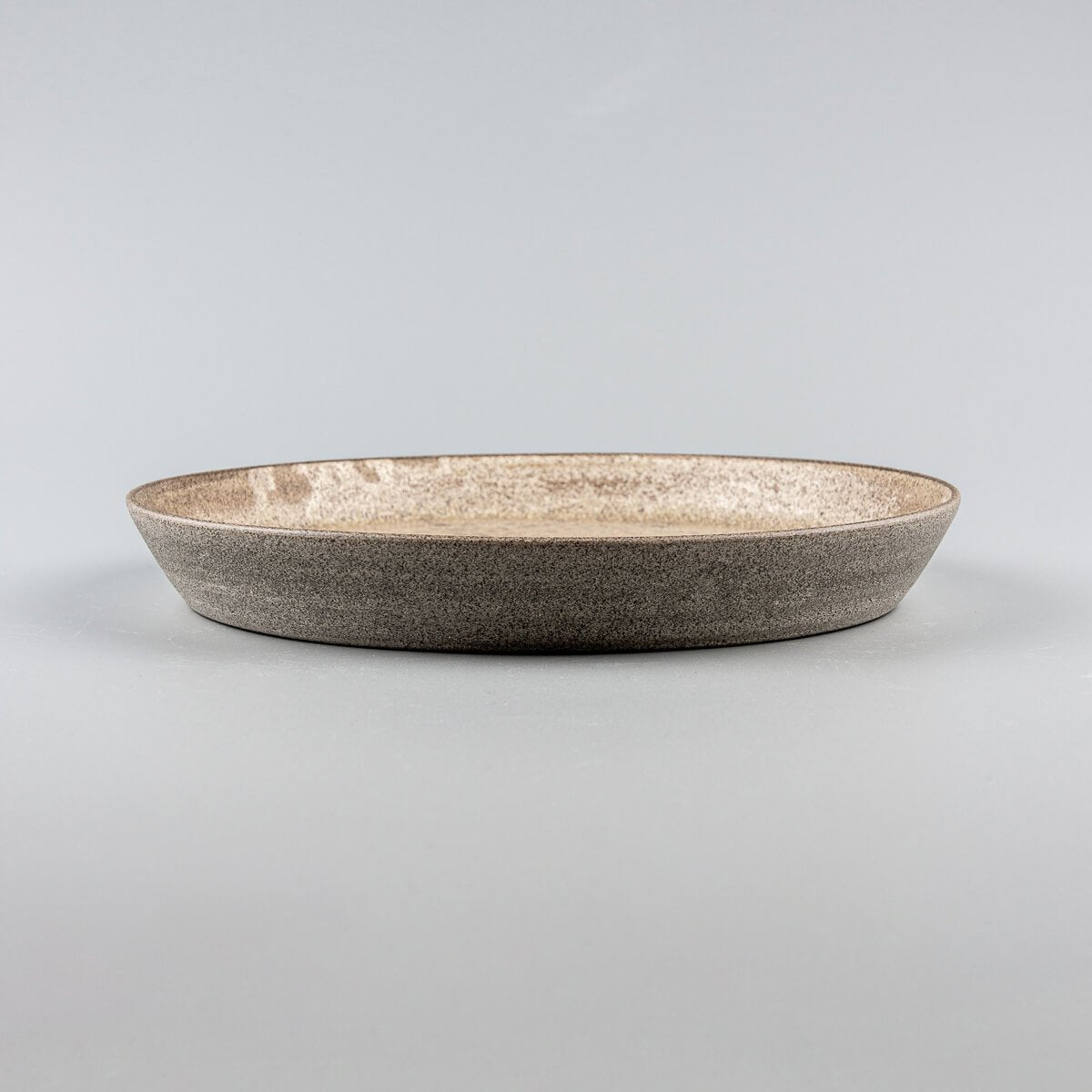 Side profile of coupe-style stoneware dinner plate with raised edges.