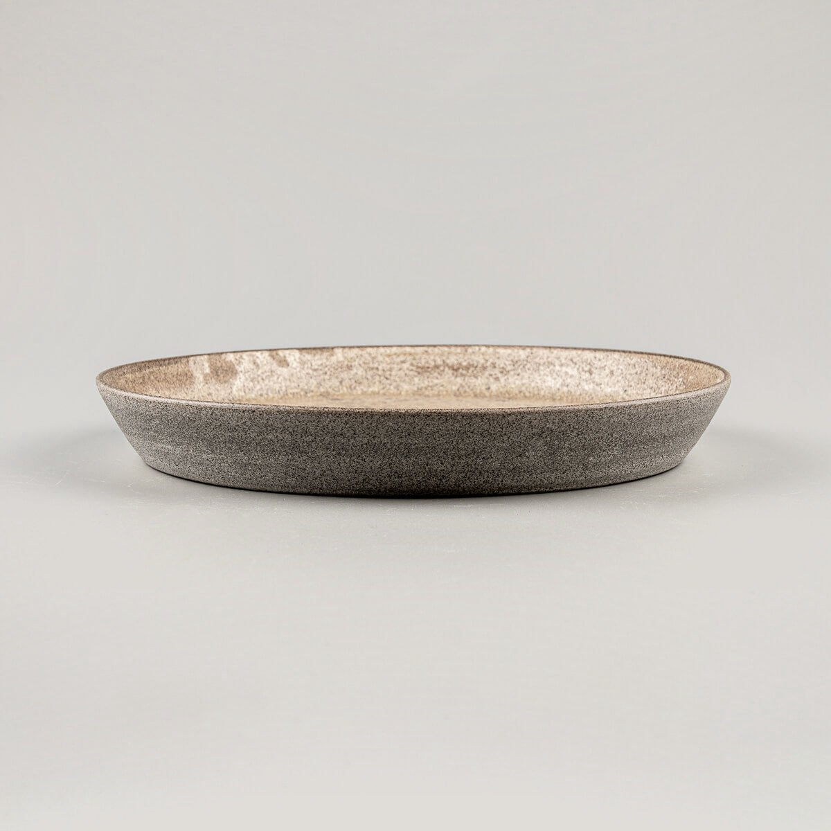 Side profile of coupe-style stoneware dinner plate with raised edges.