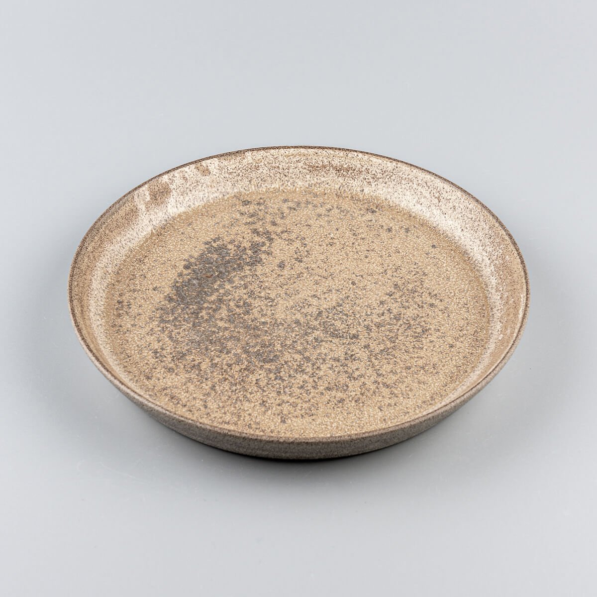 Coupe-style stoneware dinner plate with raised edges and refined handmade texture.