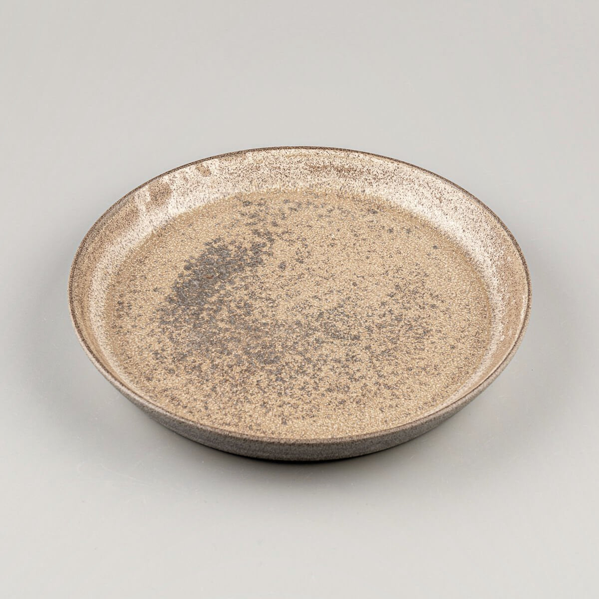Coupe-style stoneware dinner plate with raised edges and refined handmade texture.