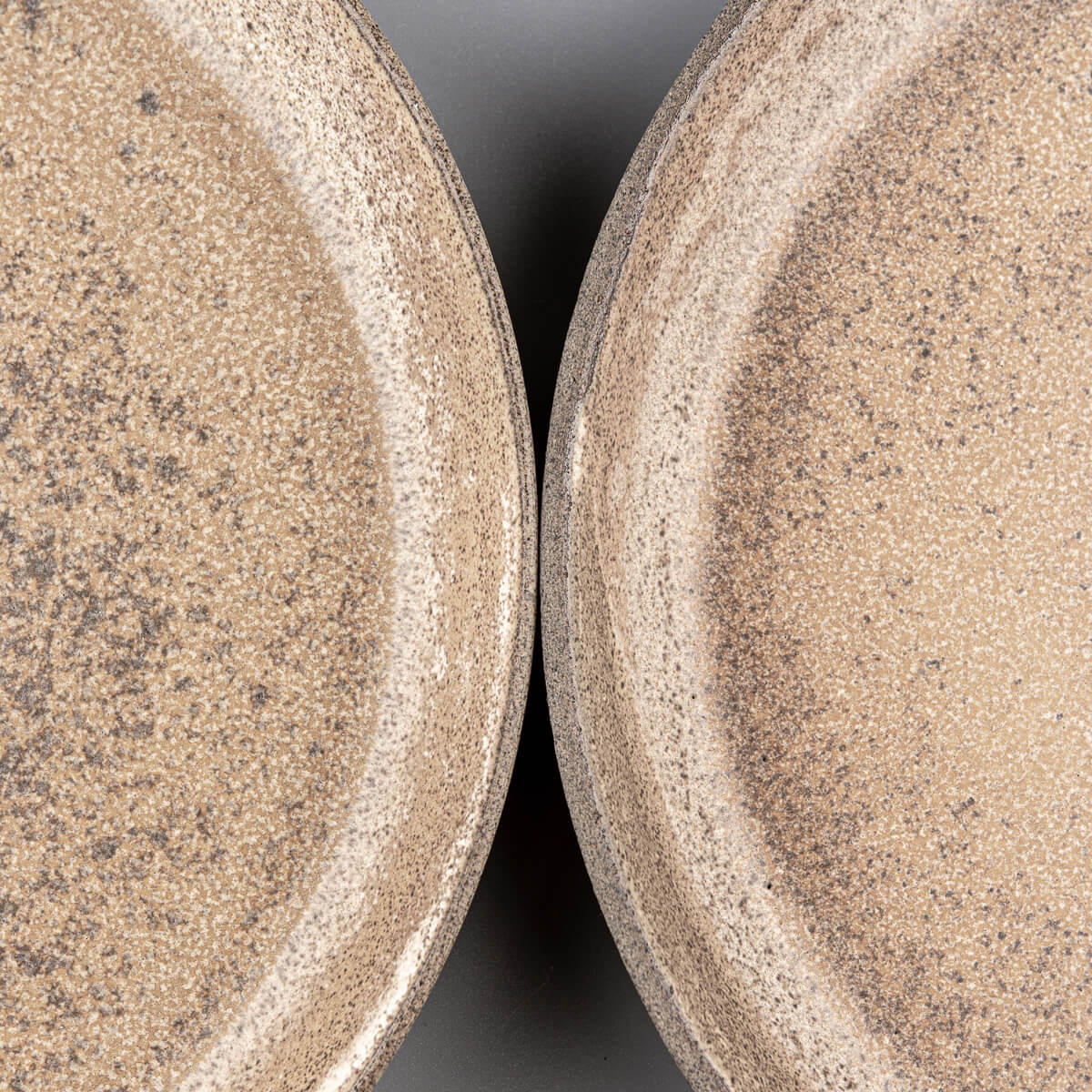 Flat-lay view of stoneware dinner plates with earthy glaze tones.