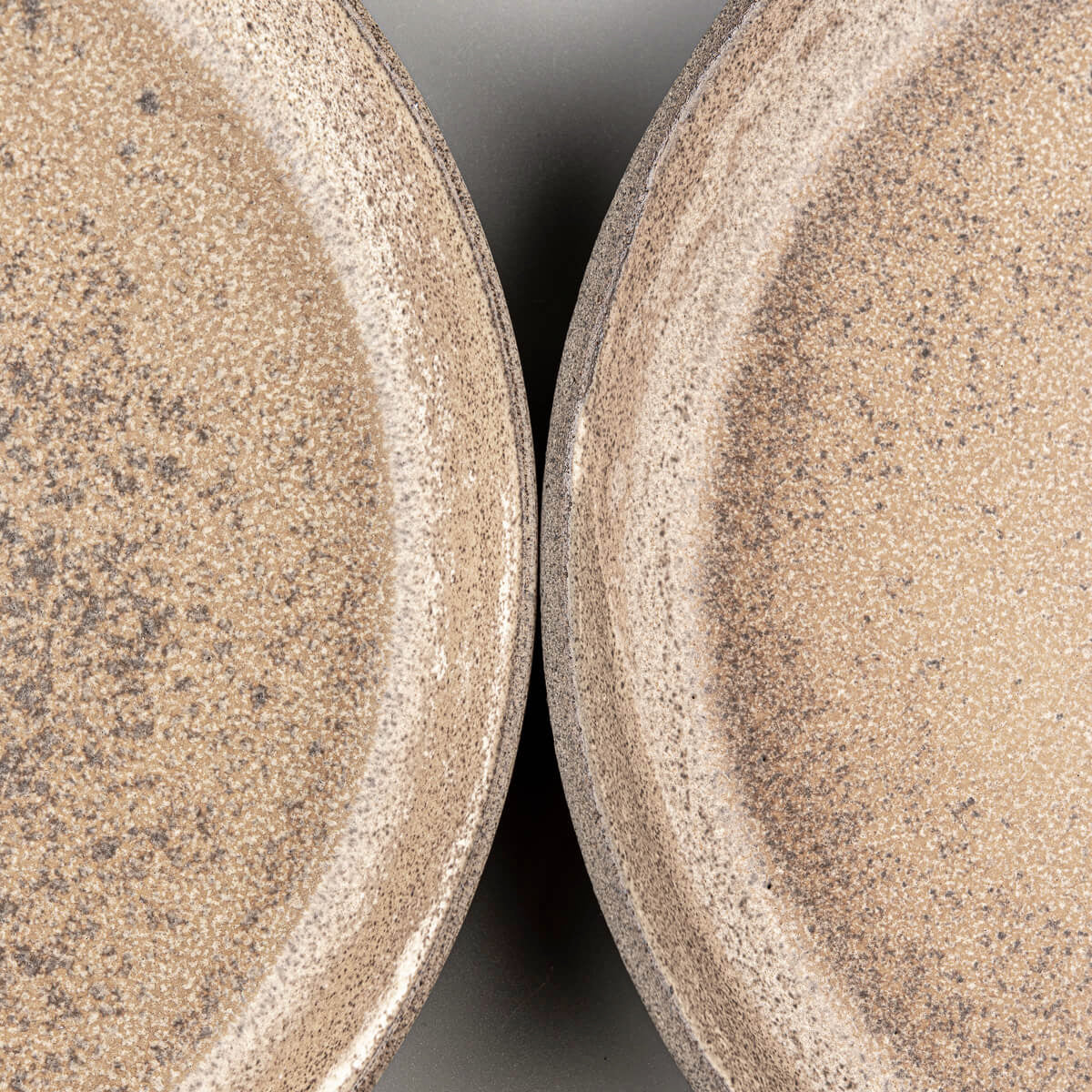 Flat-lay view of stoneware dinner plates with earthy glaze tones.
