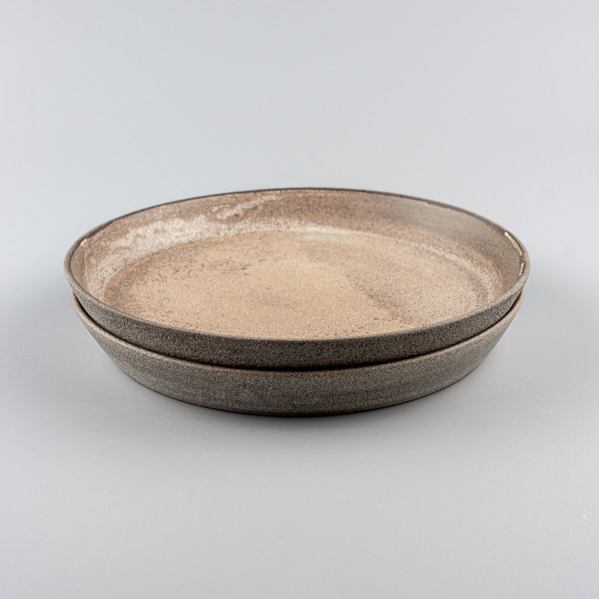 Stacked stoneware dinner plates with refined coupe design.